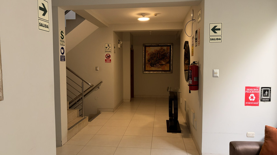 Corridor leading to the guest rooms, with safety signage and a fire extinguisher
